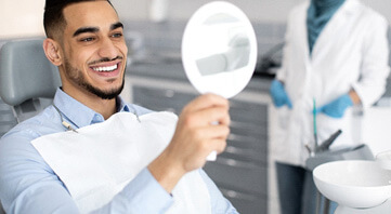 man smiling while looking at reflection in mirror