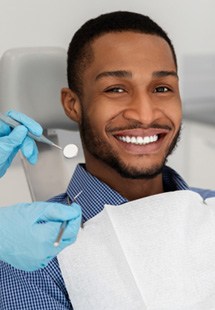 woman smiling while holding dental mirror 