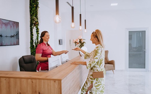 Dental receptionist assists patient at front desk